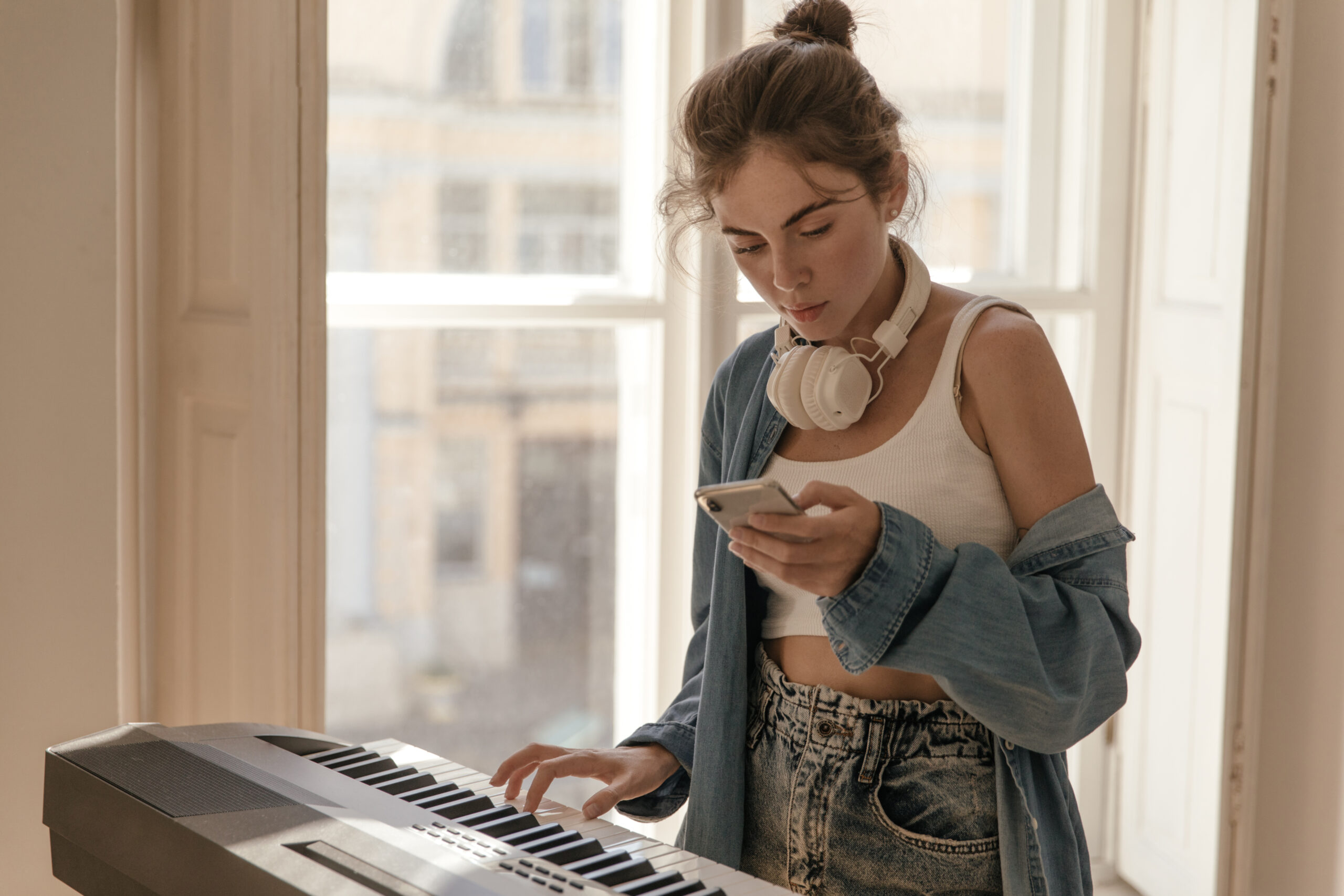 Music, instrumental, piano, hobby concept. Stylish young lady with collected hair, white top and bl