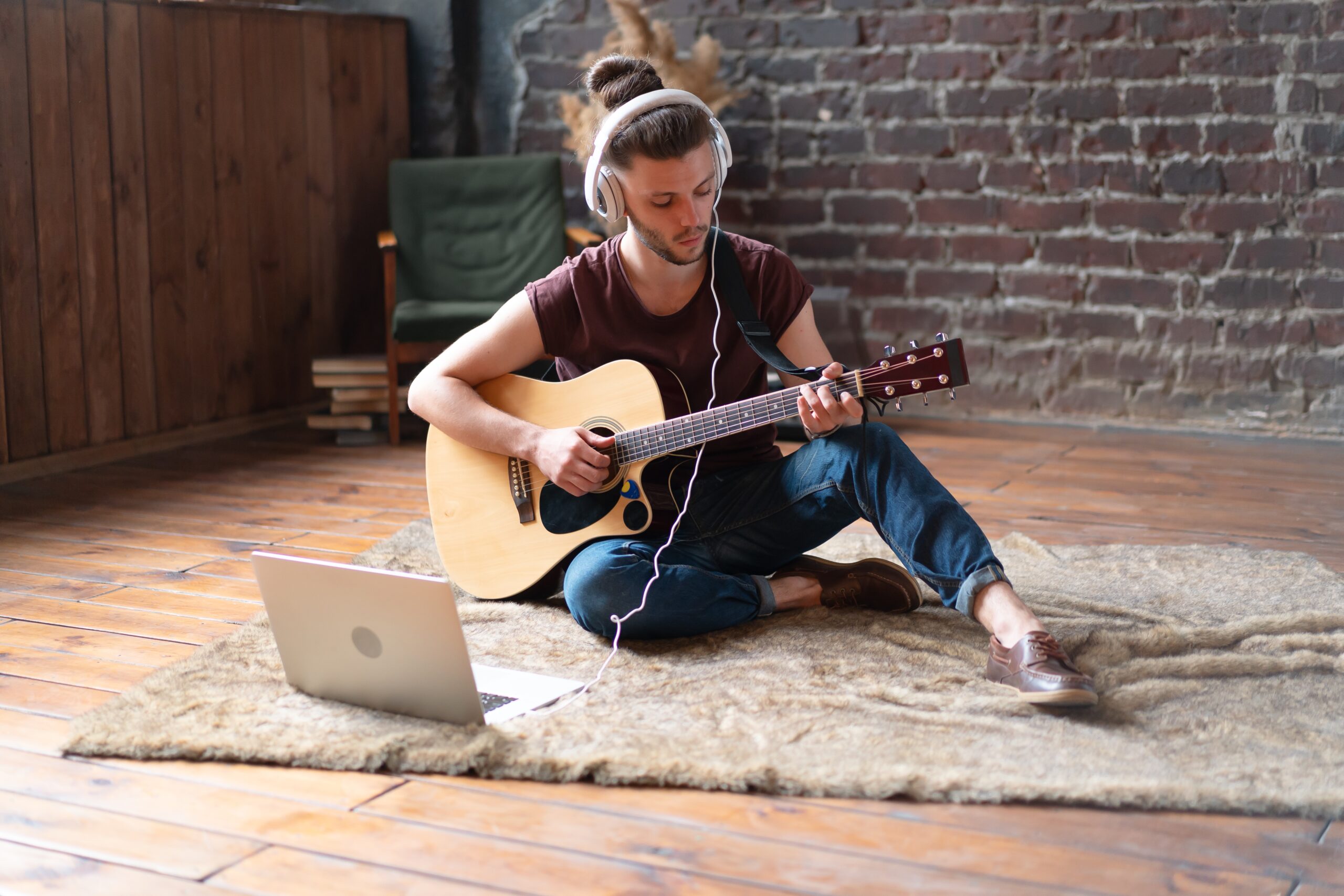 young-handsome-man-watching-guitar-tutorial-on-lap-JMGXDVZ